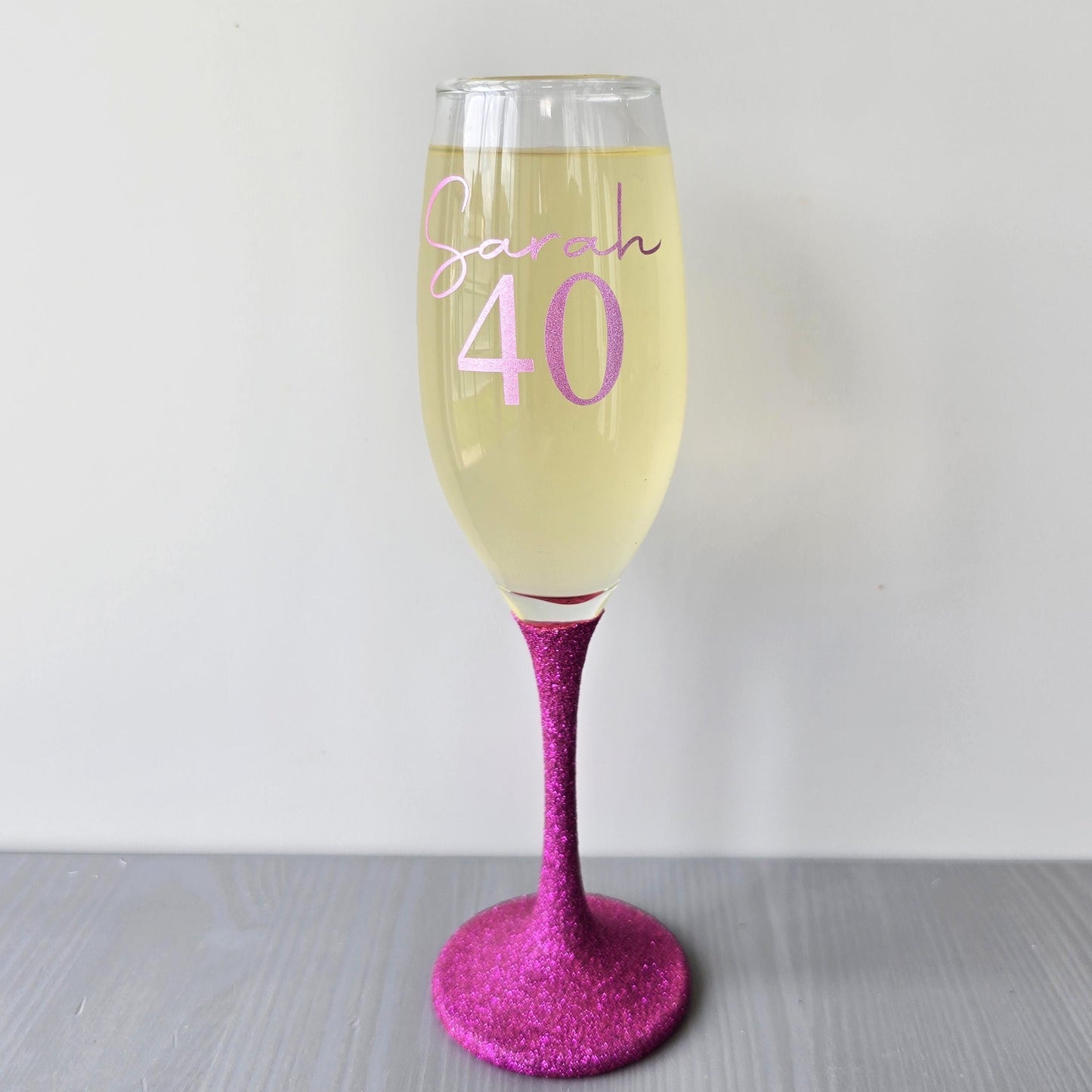 Personalised glitter stem prosecco glass or champagne flute in gold, pink, purple or Blue. Signature style custom name and an age underneath