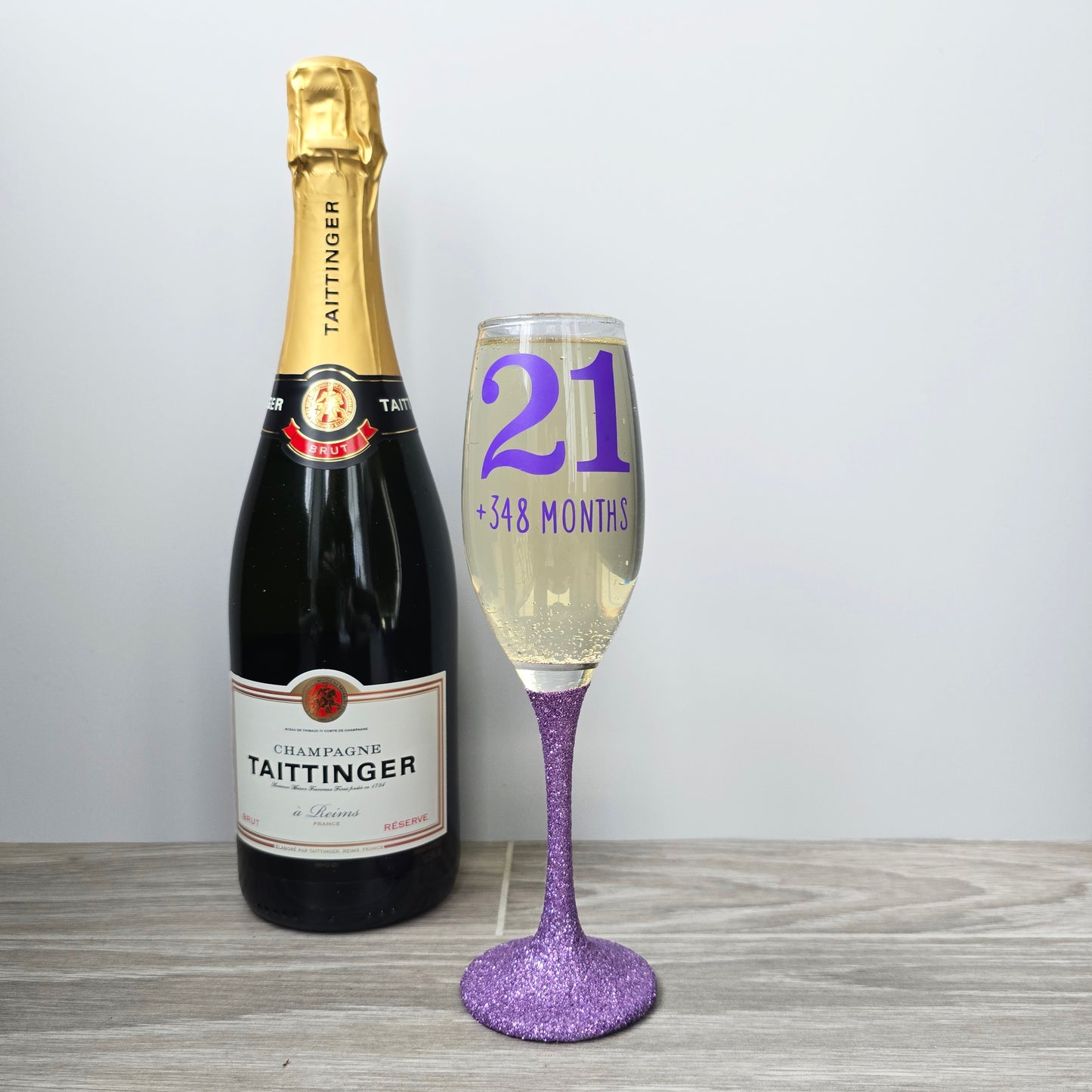 Prosecco glass or Champagne flute decorated with high shine glitter stem and personalised with 21 + the number of months to make up a 30th, 40th, 50th, 60th or 70th Birthday.