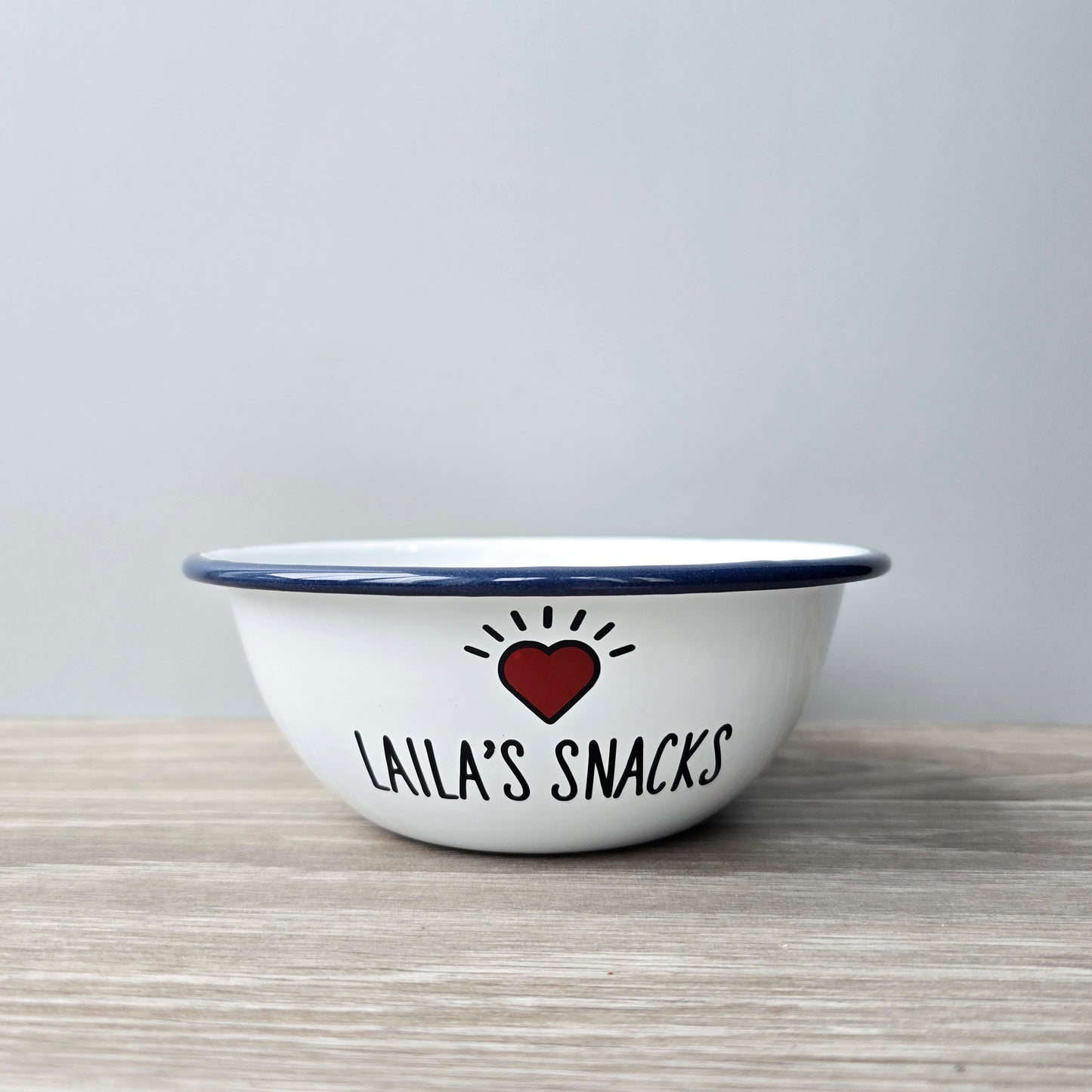 Kids Personalised white metal enamel snack bowl. White enamel metal bowl with navy blue rim. Printed with a yellow star or red heart and a name with snacks written underneath. Perfect for popcorn, sweets, crisps or general snacks.