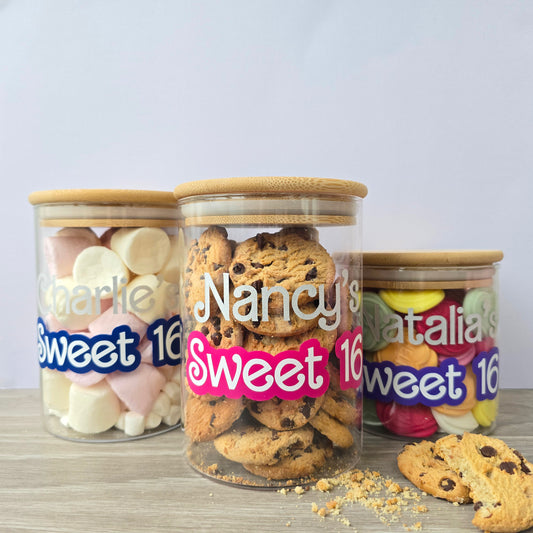 Personalised small and medium sized glass jar with wooden, bamboo suction lid with a name in silver shimmer text and 'Sweet 16' in pink, blue or purple bubble font underneath