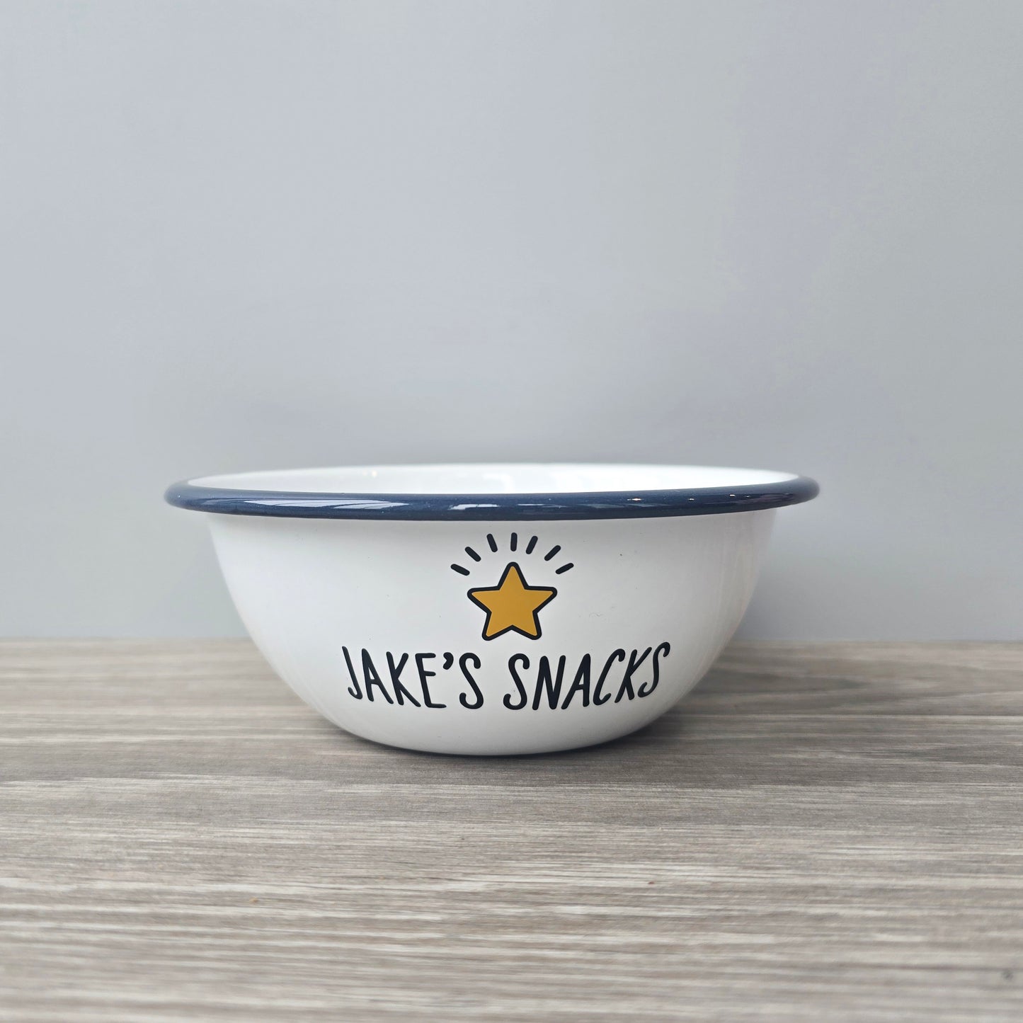 Kids Personalised white metal enamel snack bowl. White enamel metal bowl with navy blue rim. Printed with a yellow star or red heart and a name with snacks written underneath. Perfect for popcorn, sweets, crisps or general snacks.