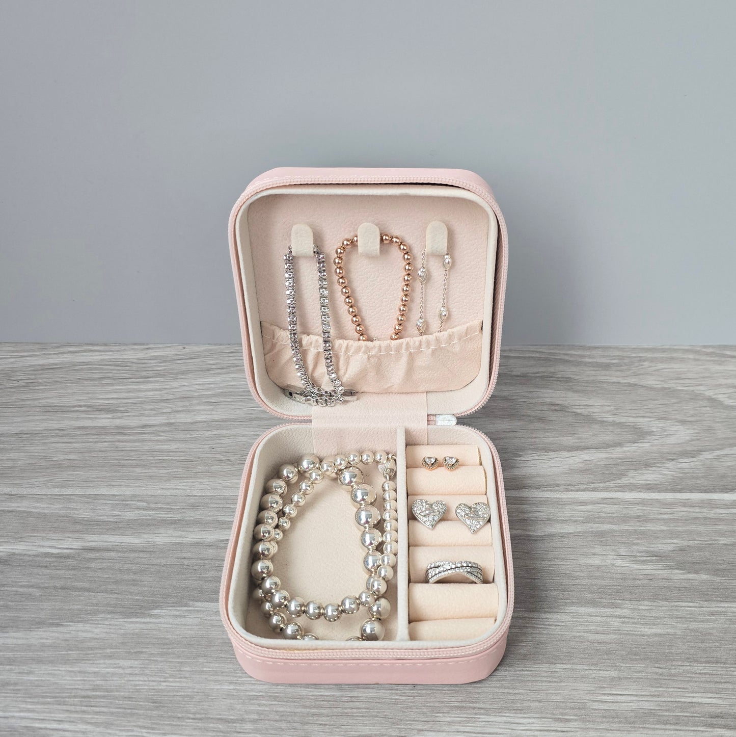 Faux leather, travel jewellery box personalised with a name in the middle of a decorative circle, decorated with hearts. Travel size jewellery case with zip and internal jewellery dividers.