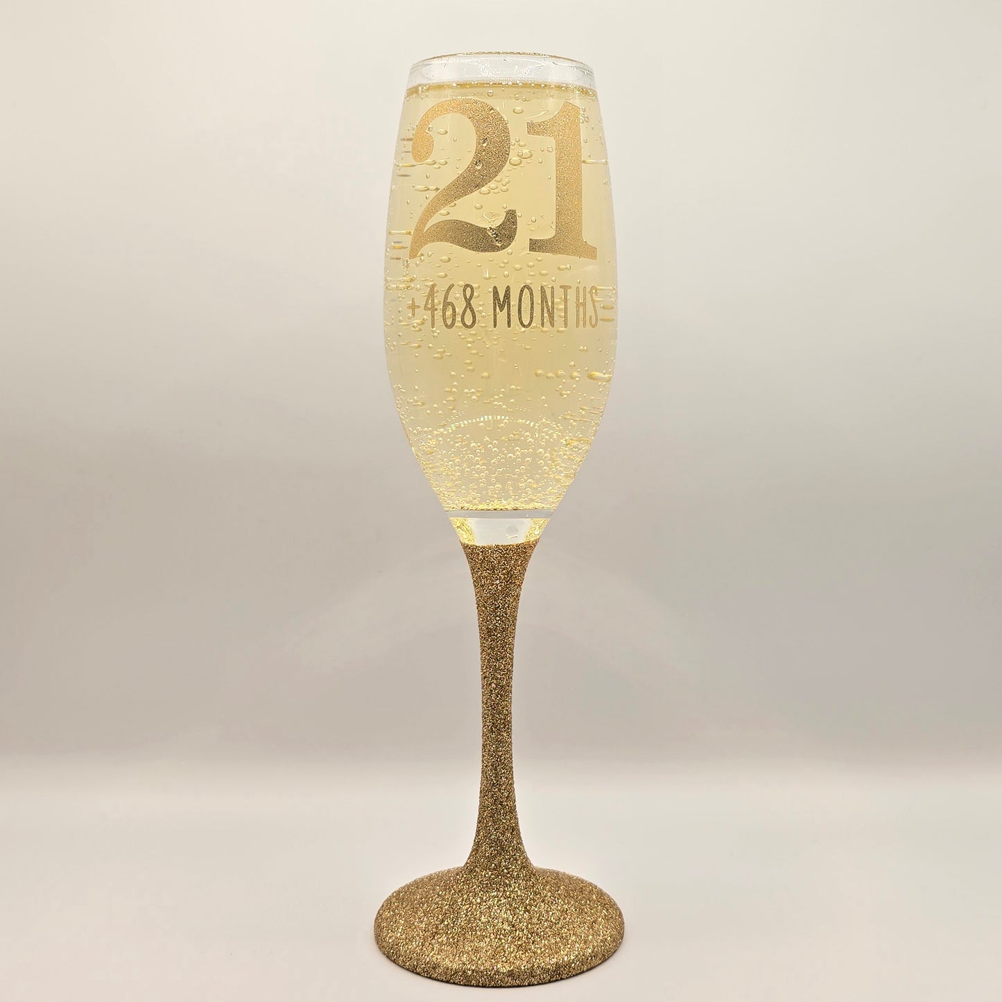 Prosecco glass or Champagne flute decorated with high shine glitter stem and personalised with 21 + the number of months to make up a 30th, 40th, 50th, 60th or 70th Birthday.