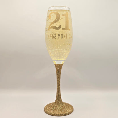 Prosecco glass or Champagne flute decorated with high shine glitter stem and personalised with 21 + the number of months to make up a 30th, 40th, 50th, 60th or 70th Birthday.