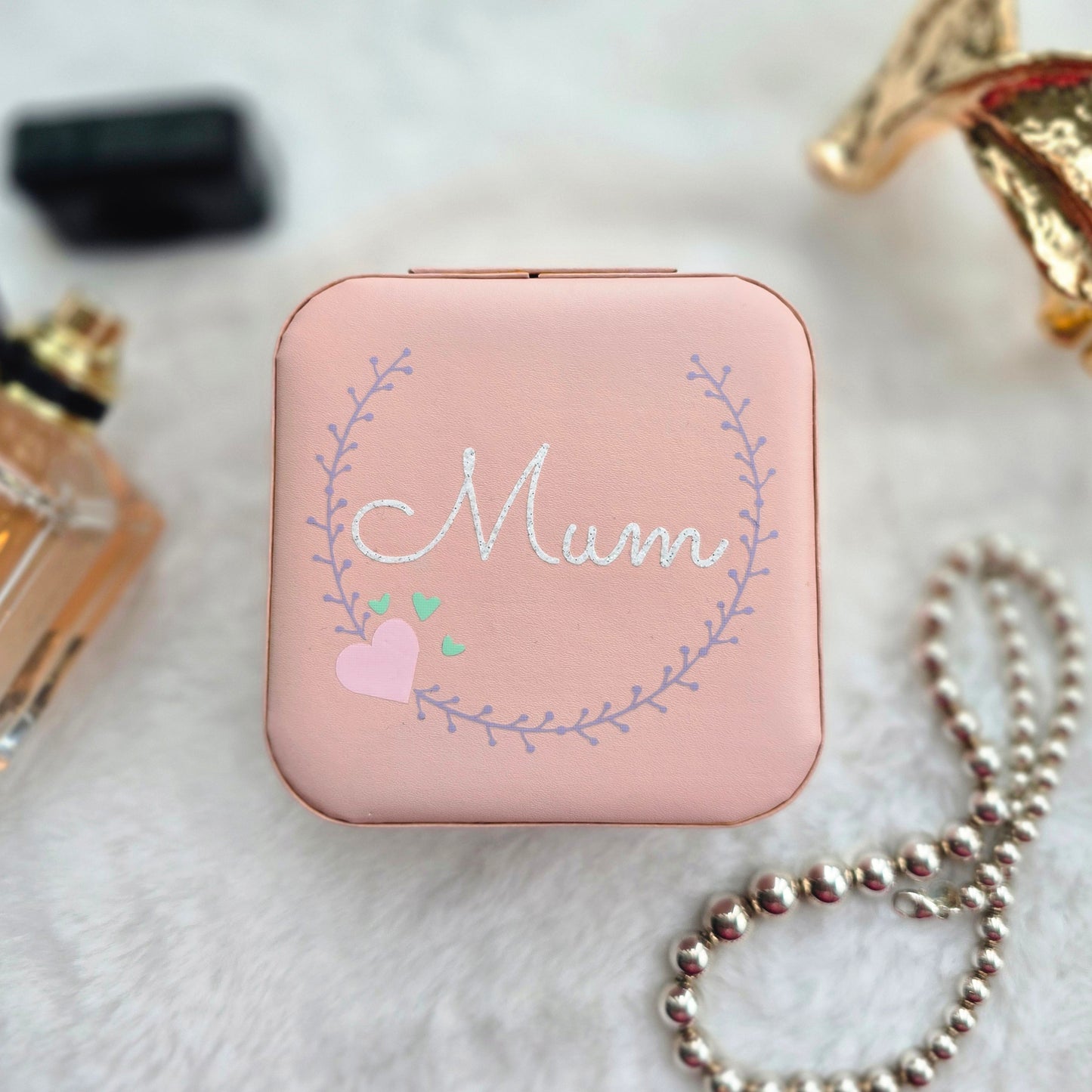 Faux leather, travel jewellery box personalised with a name in the middle of a decorative circle, decorated with hearts. Travel size jewellery case with zip and internal jewellery dividers.
