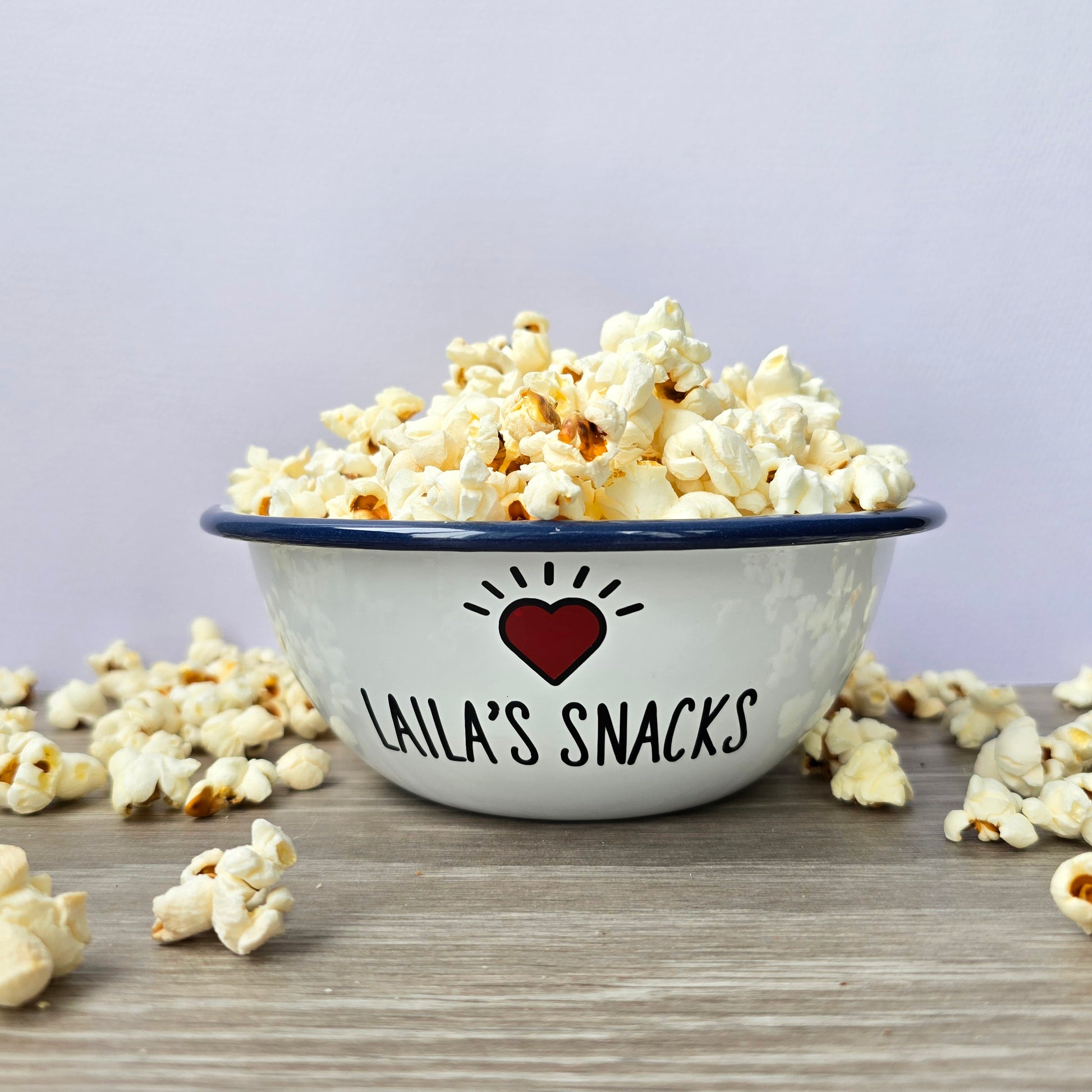Kids Personalised white metal enamel snack bowl. White enamel metal bowl with navy blue rim. Printed with a yellow star or red heart and a name with snacks written underneath. Perfect for popcorn, sweets, crisps or general snacks.