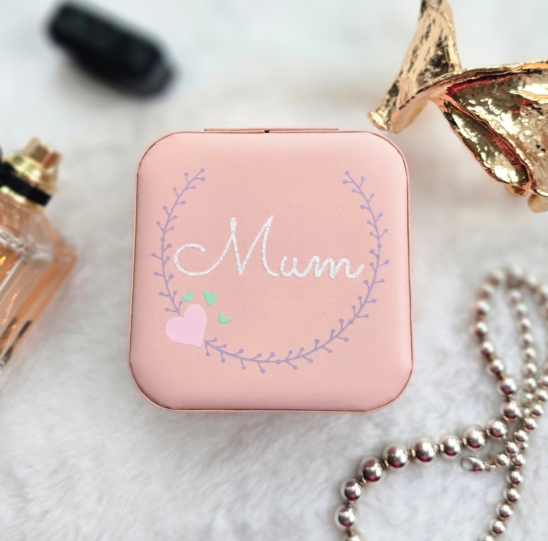 Faux leather, travel jewellery box personalised with a name in the middle of a decorative circle, decorated with hearts. Travel size jewellery case with zip and internal jewellery dividers.