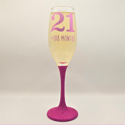 Prosecco glass or Champagne flute decorated with high shine glitter stem and personalised with 21 + the number of months to make up a 30th, 40th, 50th, 60th or 70th Birthday.