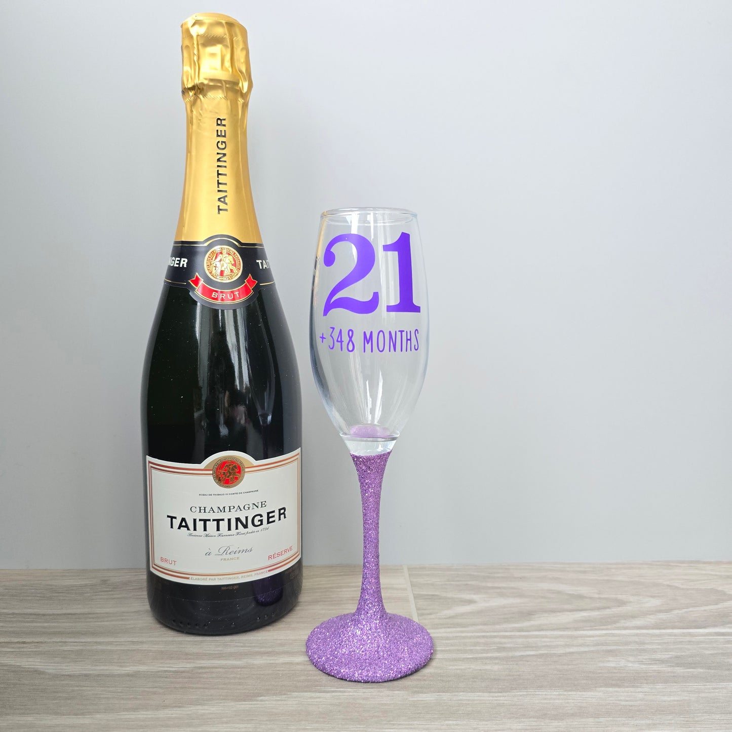 Prosecco glass or Champagne flute decorated with high shine glitter stem and personalised with 21 + the number of months to make up a 30th, 40th, 50th, 60th or 70th Birthday.