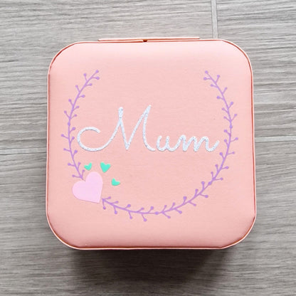 Faux leather, travel jewellery box personalised with a name in the middle of a decorative circle, decorated with hearts. Travel size jewellery case with zip and internal jewellery dividers.