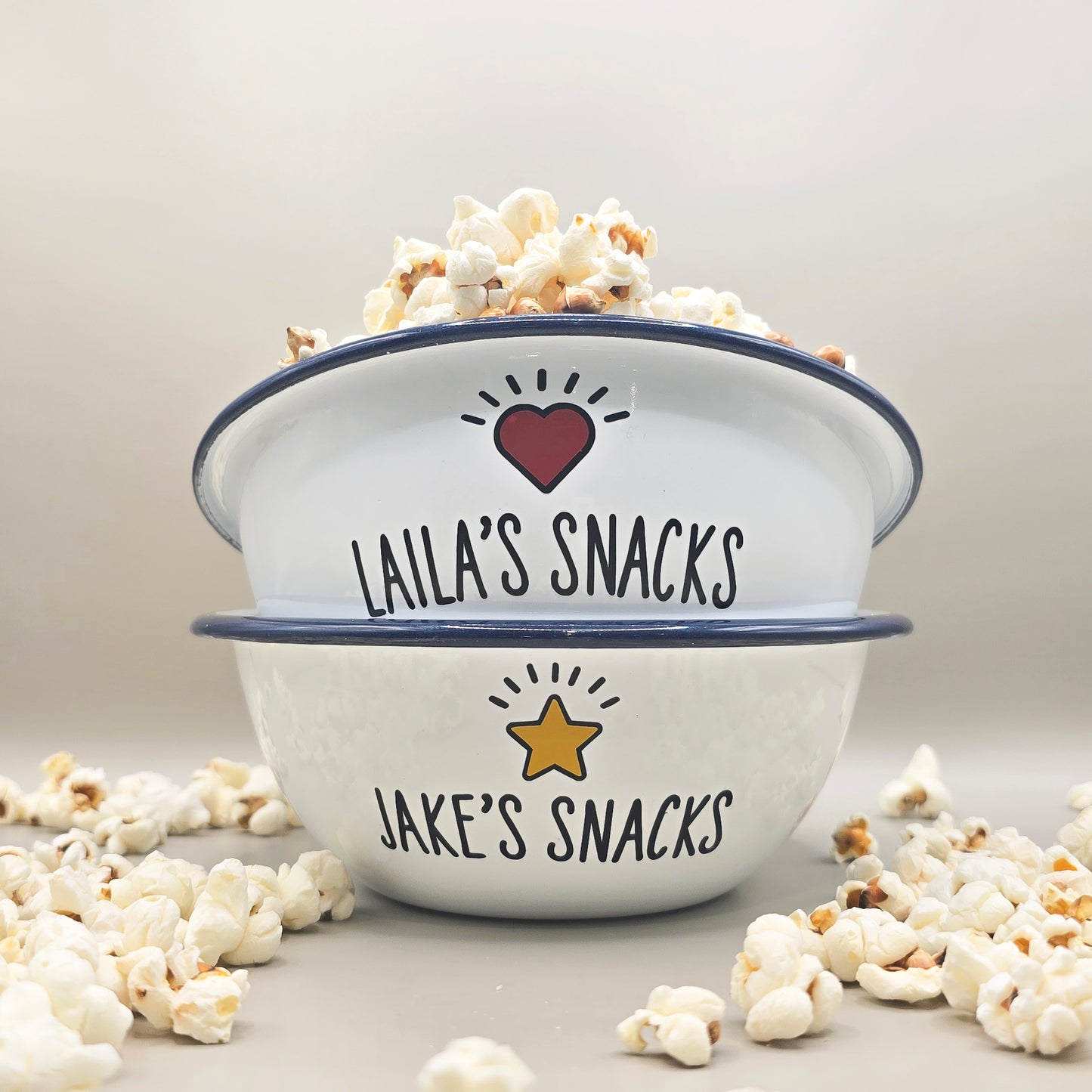 Kids Personalised white metal enamel snack bowl. White enamel metal bowl with navy blue rim. Printed with a yellow star or red heart and a name with snacks written underneath. Perfect for popcorn, sweets, crisps or general snacks.