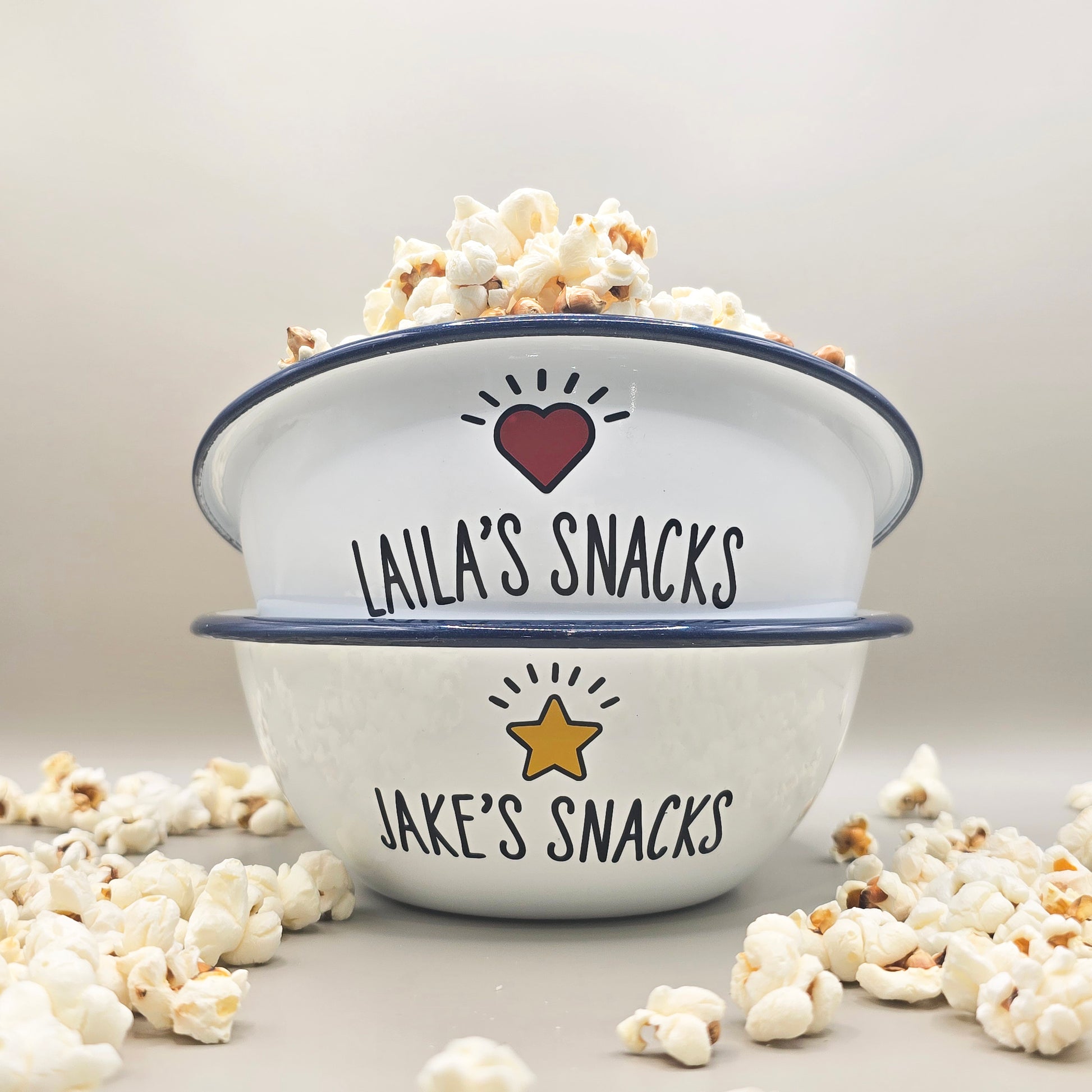 Kids Personalised white metal enamel snack bowl. White enamel metal bowl with navy blue rim. Printed with a yellow star or red heart and a name with snacks written underneath. Perfect for popcorn, sweets, crisps or general snacks.