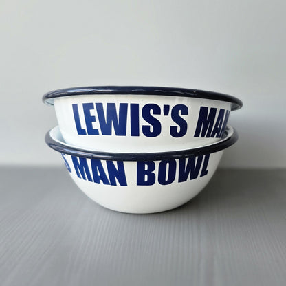 White enamel metal bowl with blue rim and text personalised with a name and 'MAN BOWL' on a grey surface.