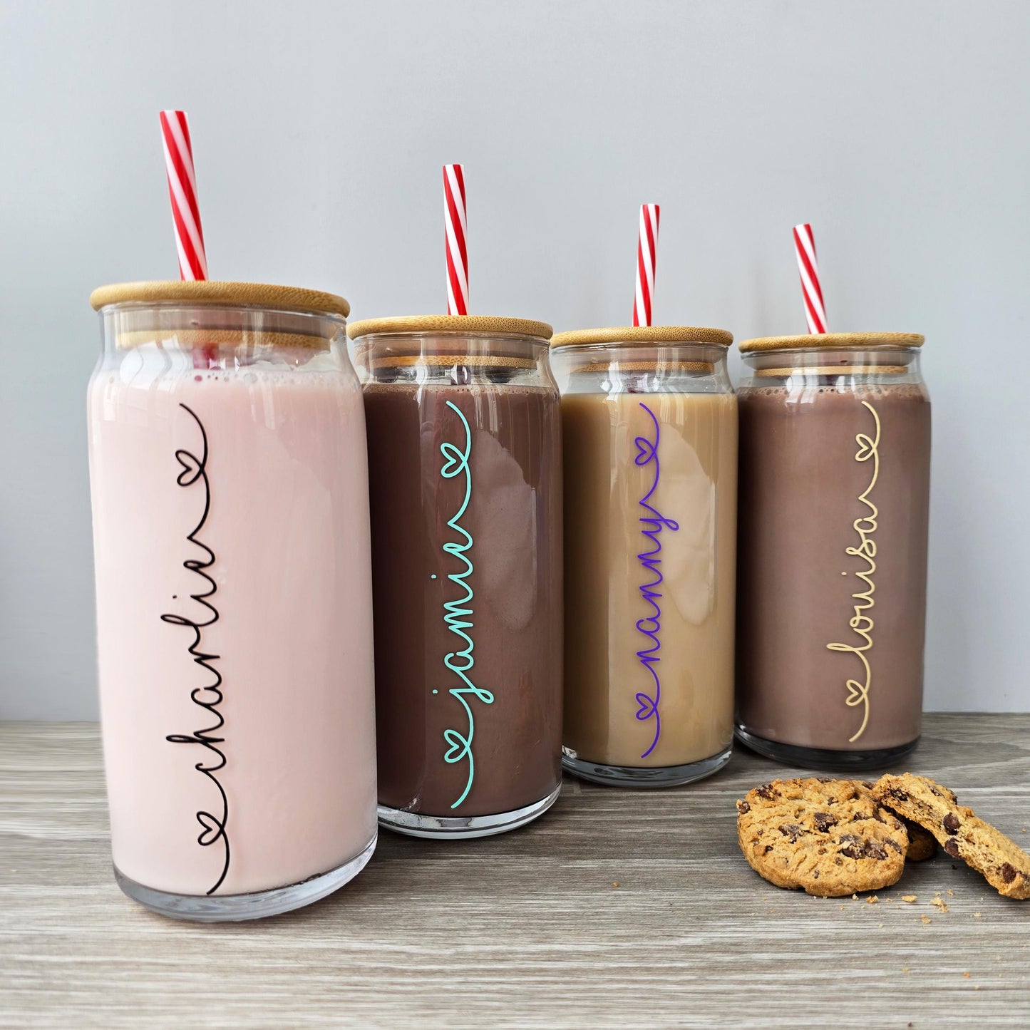 Personalised glass can drink tumbler with a bamboo suction lid and red and white reusable straw. Name printed in decorative font, in a range of colours, printed along the glass.