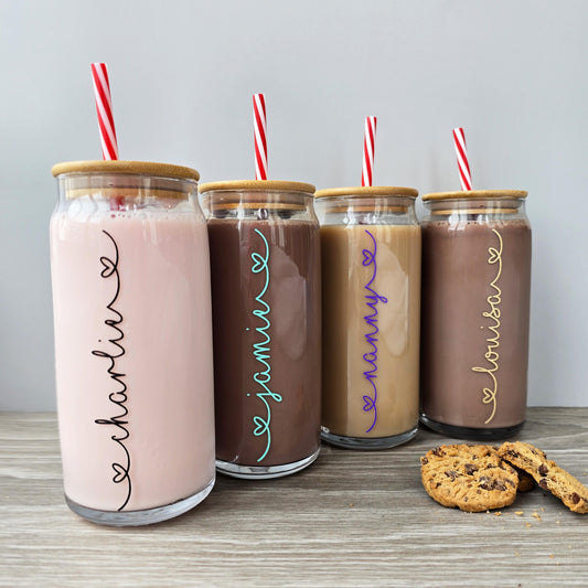 Personalised glass can drink tumbler with a bamboo suction lid and red and white reusable straw. Name printed in decorative font, in a range of colours, printed along the glass.