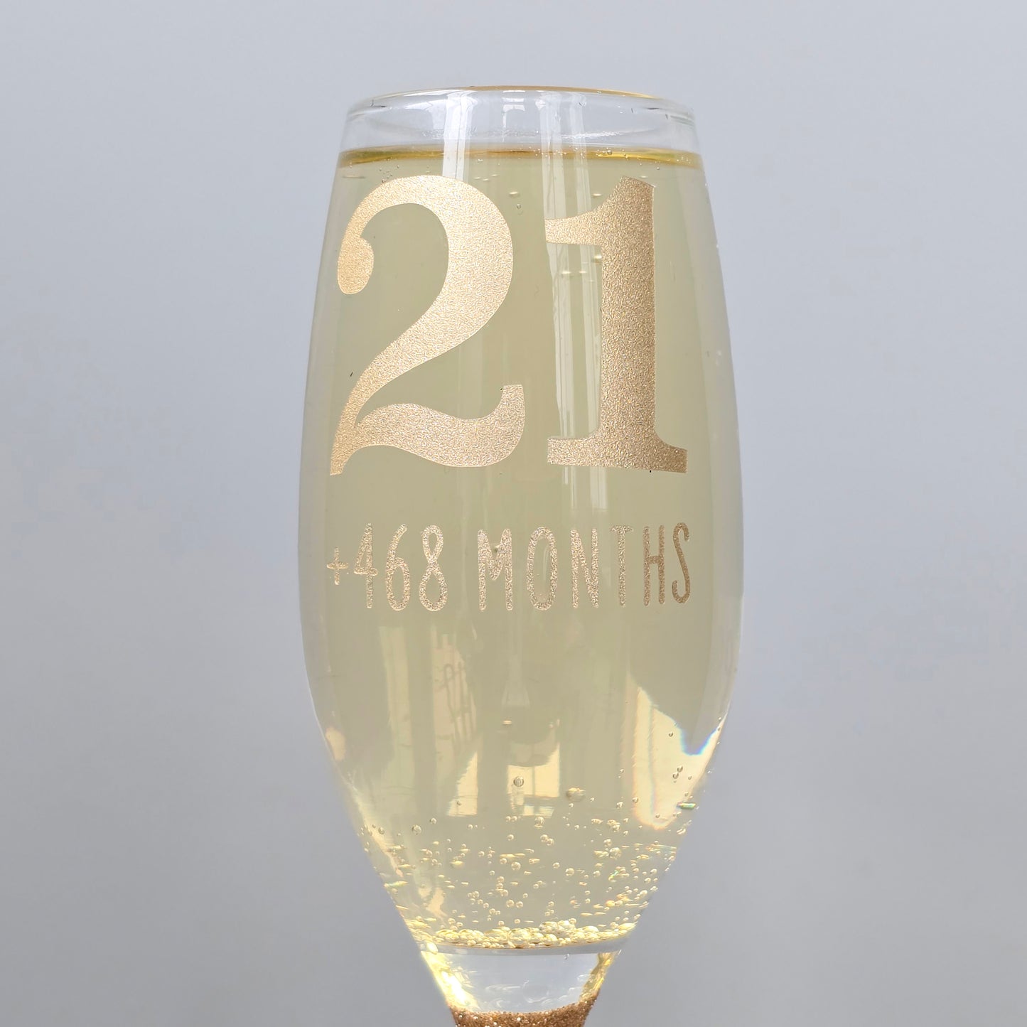 Prosecco glass or Champagne flute decorated with high shine glitter stem and personalised with 21 + the number of months to make up a 30th, 40th, 50th, 60th or 70th Birthday.