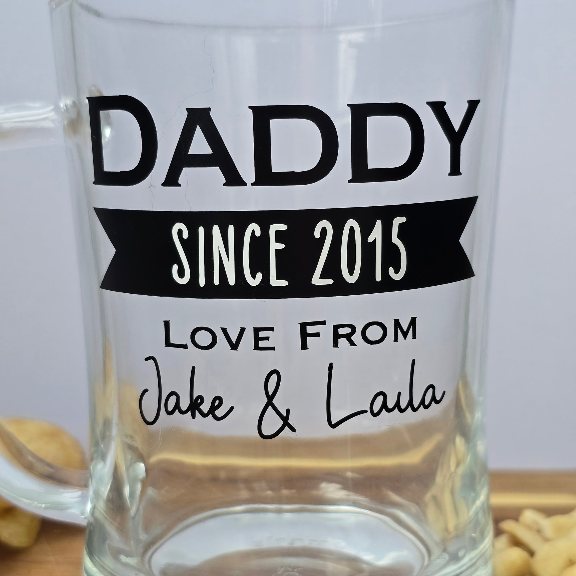 Glass beer tankard personalised with a name, year and signed from the gift giver in black vinyl on clear glass. Sturdy, heavy, clear glass stein with mixed font design. 