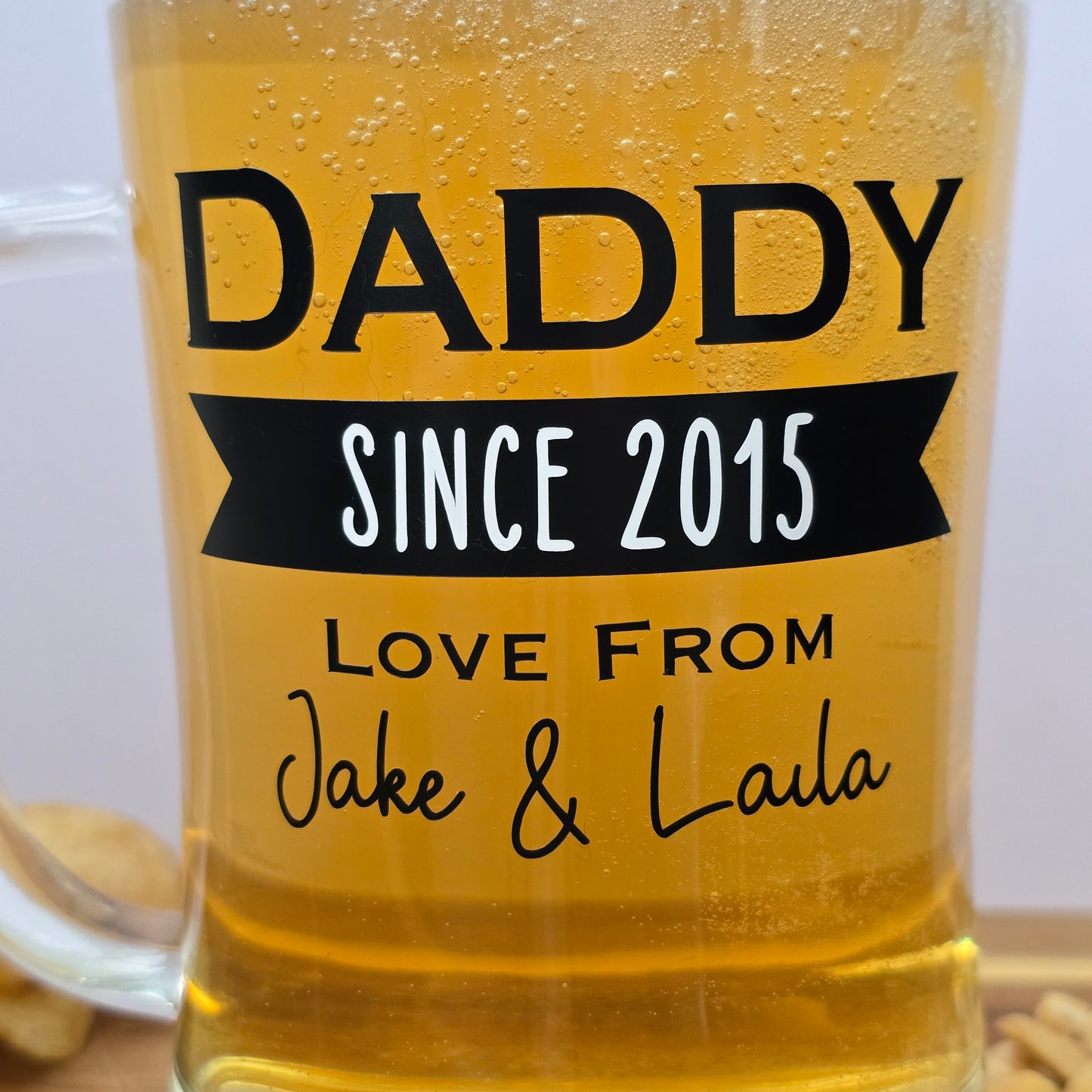 Glass beer tankard personalised with a name, year and signed from the gift giver in black vinyl on clear glass. Sturdy, heavy, clear glass stein with mixed font design. 