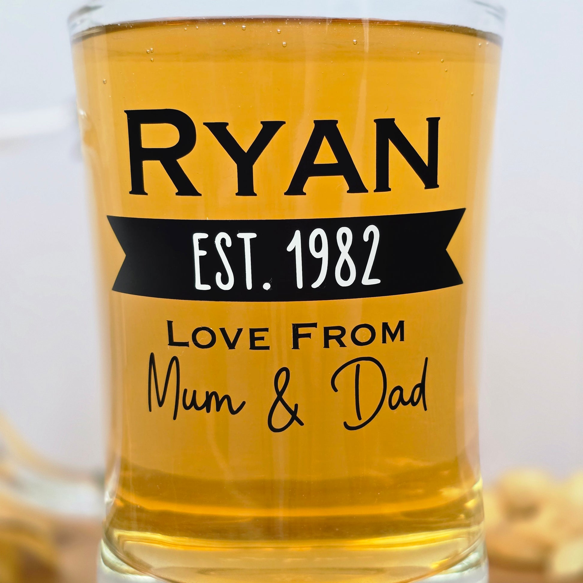Glass beer tankard personalised with a name, year and signed from the gift giver in black vinyl on clear glass. Sturdy, heavy, clear glass stein with mixed font design. 
