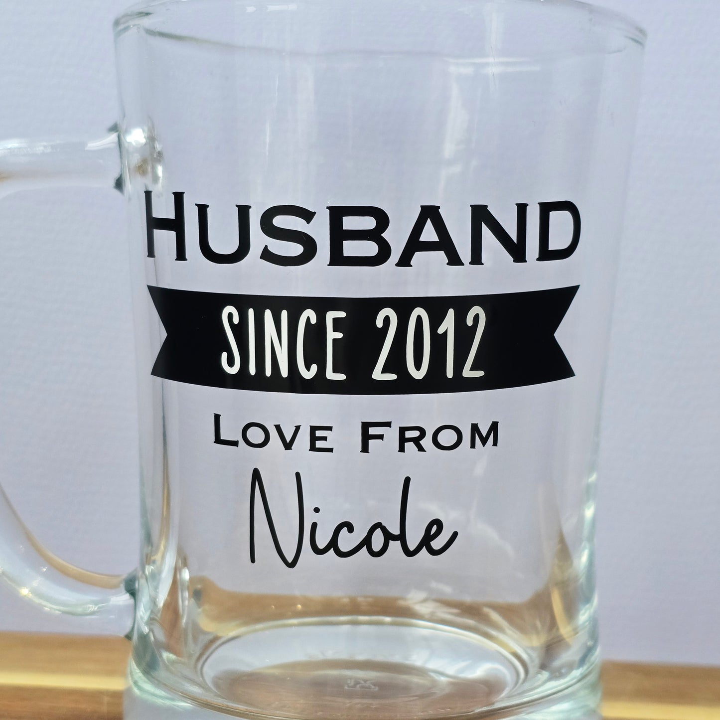 Glass beer tankard personalised with a name, year and signed from the gift giver in black vinyl on clear glass. Sturdy, heavy, clear glass stein with mixed font design. 