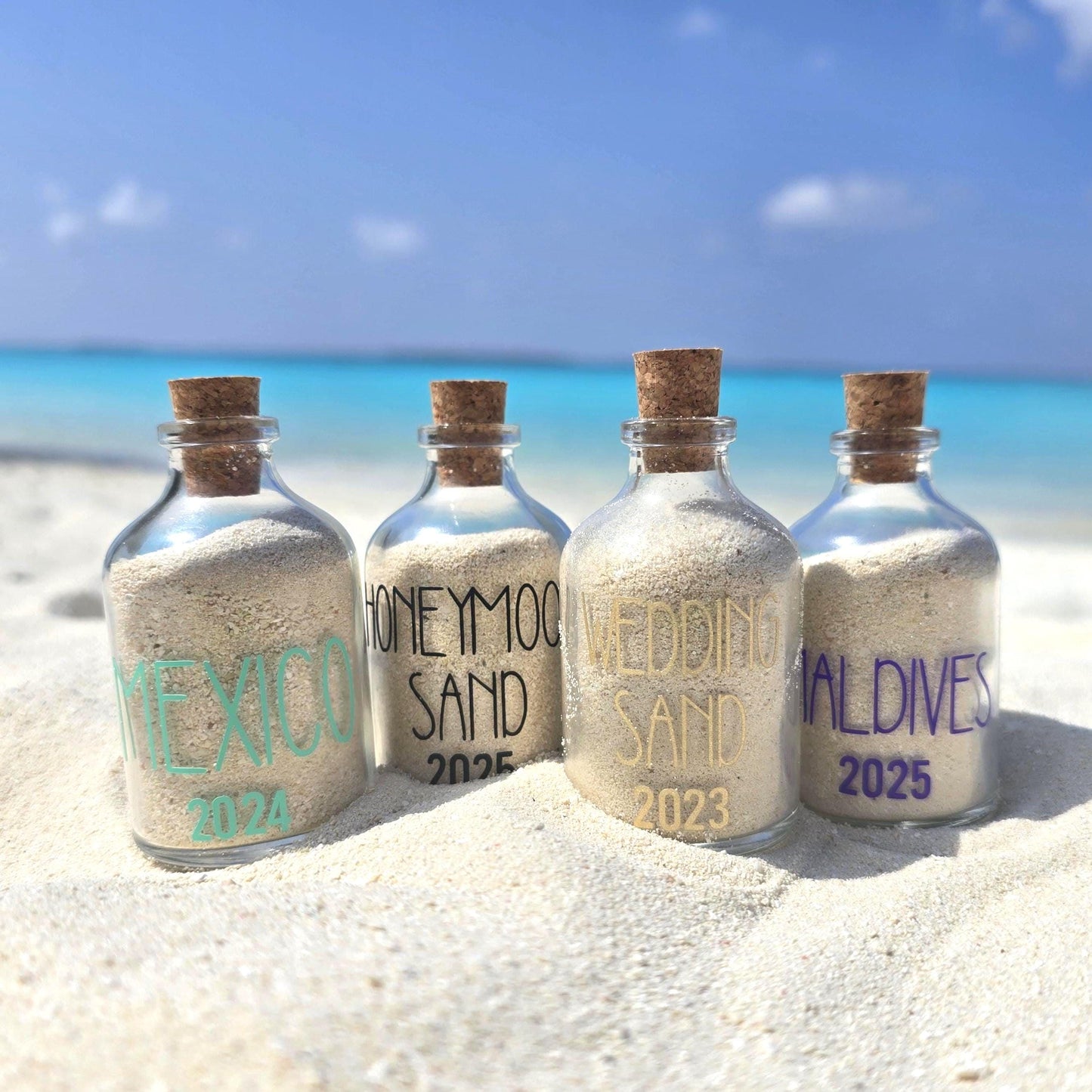 Four bottles filled with sand from different locations on a beach