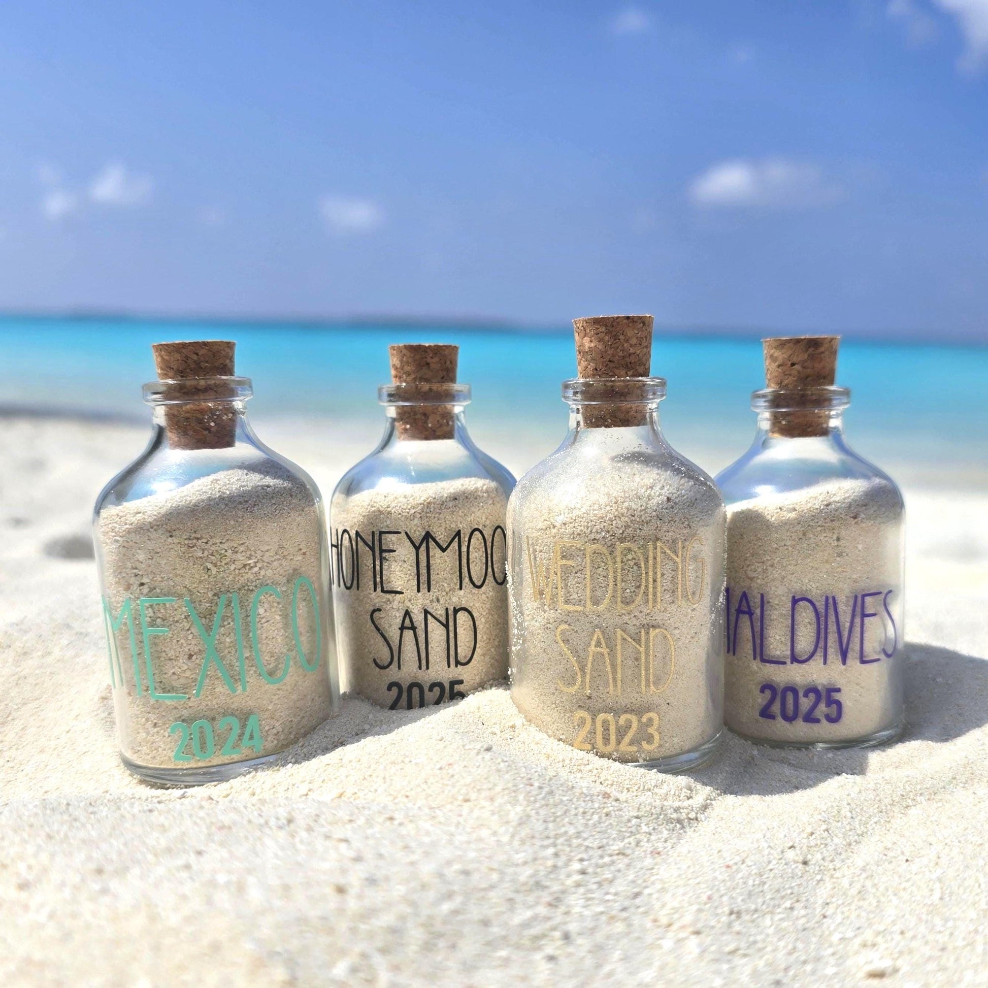 Four bottles filled with sand from different locations on a beach