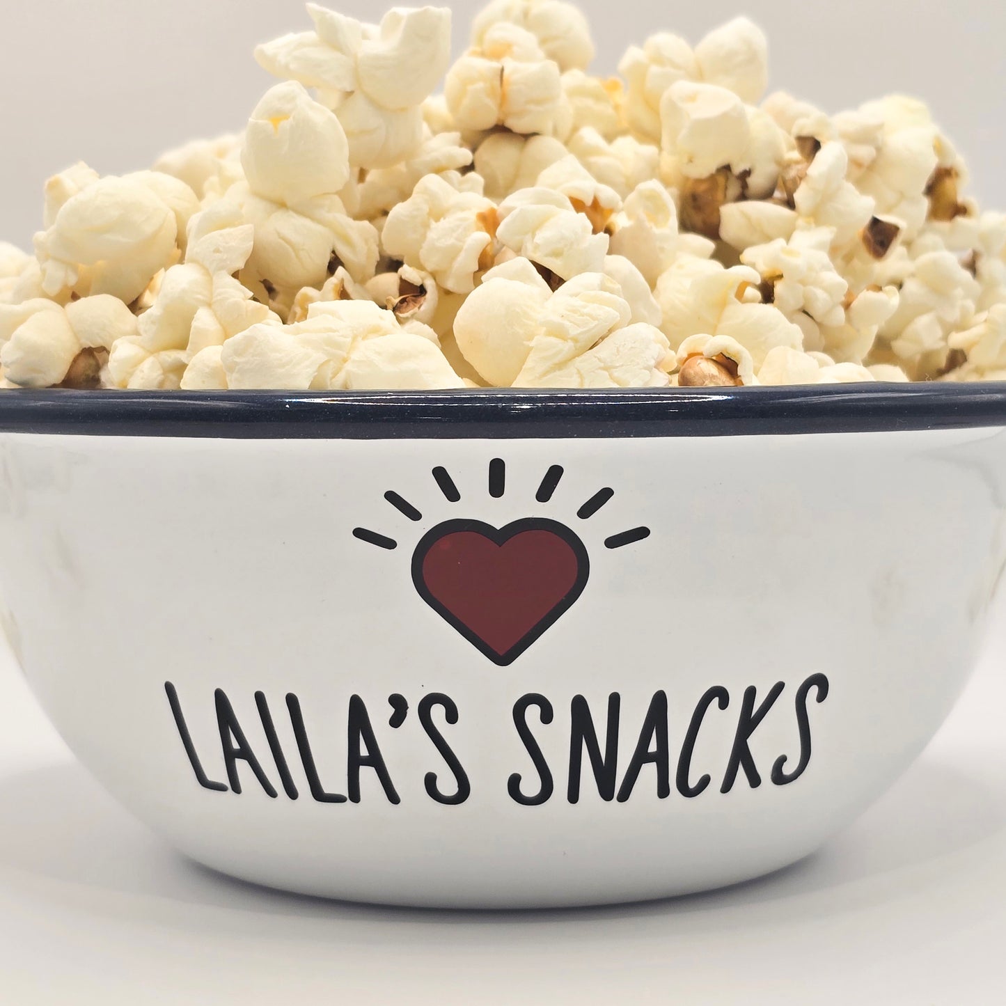 Kids Personalised white metal enamel snack bowl. White enamel metal bowl with navy blue rim. Printed with a yellow star or red heart and a name with snacks written underneath. Perfect for popcorn, sweets, crisps or general snacks.