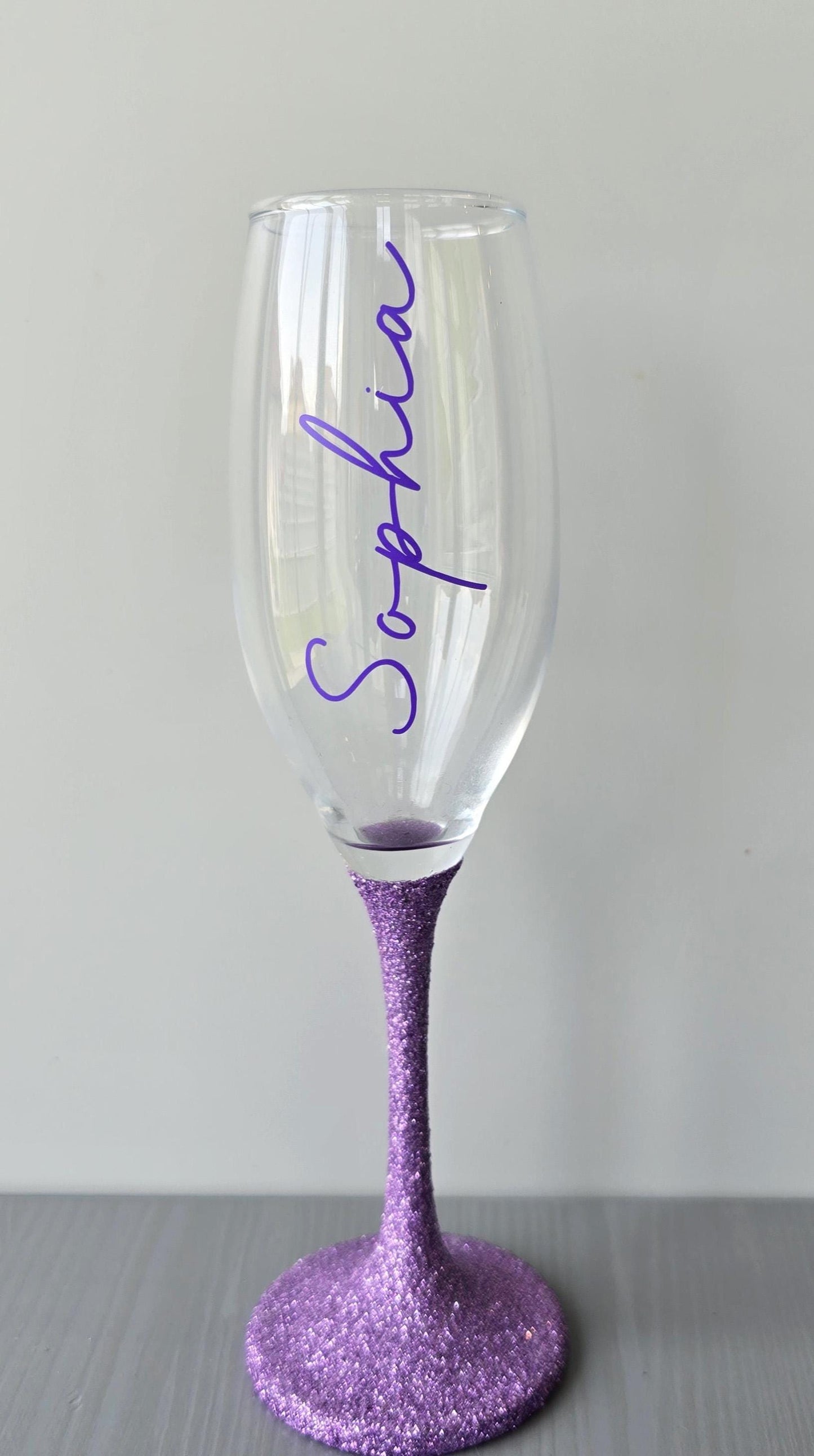 Personalised glitter stem prosecco or champagne flute glasses with a name in glitter or metallic decorative font on the side of the glass.