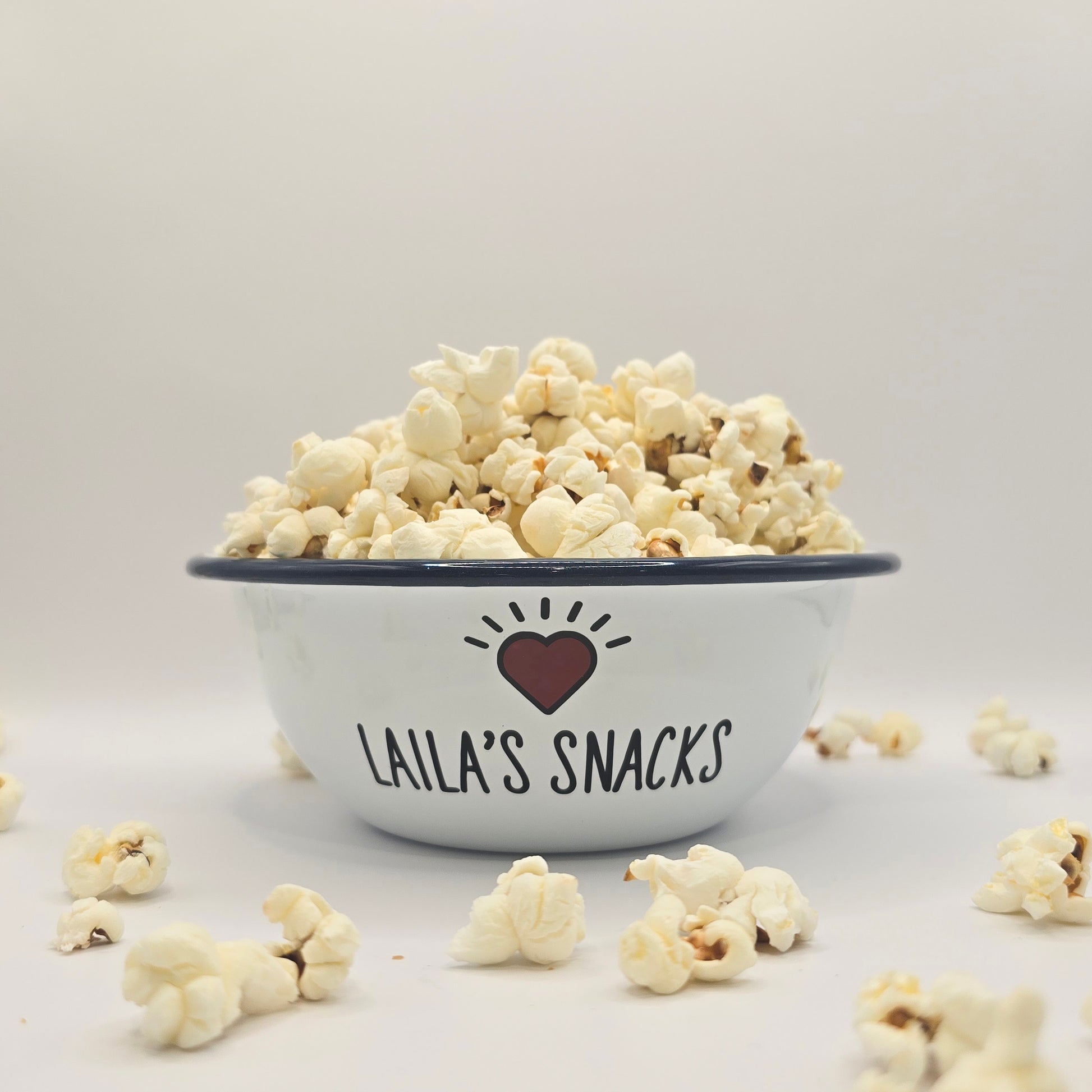 Kids Personalised white metal enamel snack bowl. White enamel metal bowl with navy blue rim. Printed with a yellow star or red heart and a name with snacks written underneath. Perfect for popcorn, sweets, crisps or general snacks.