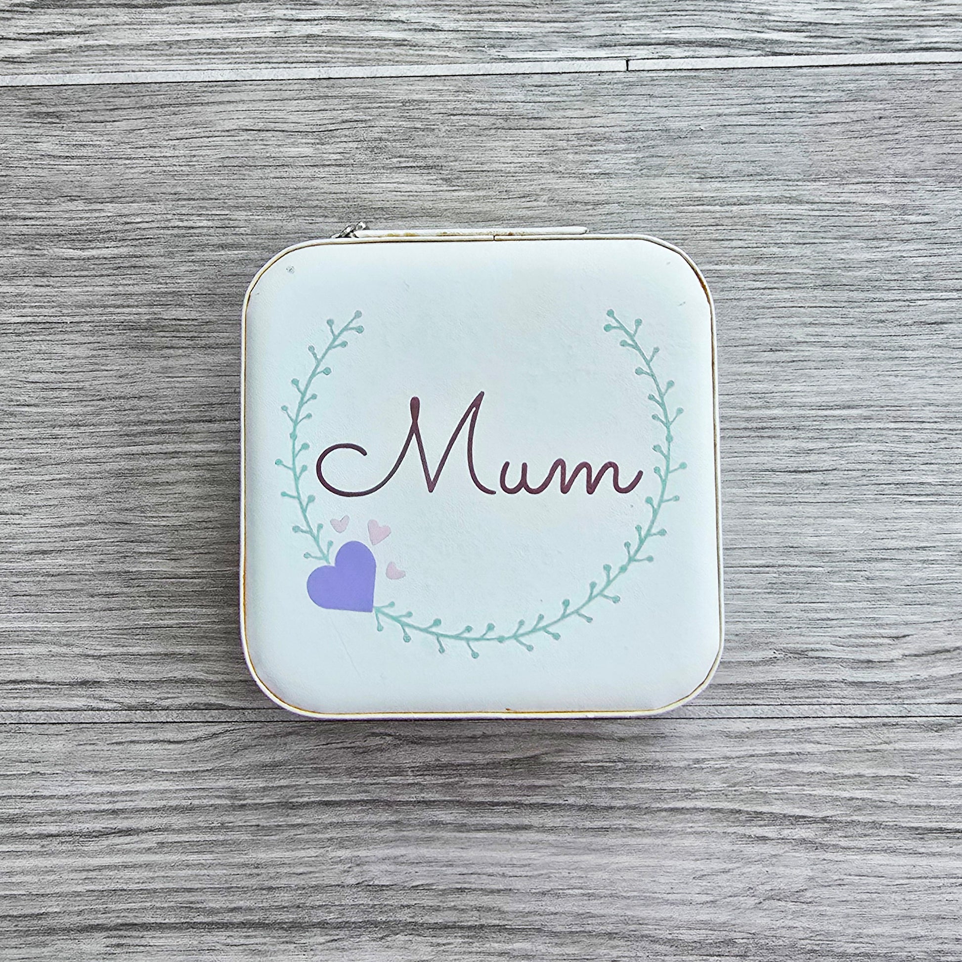 Faux leather, travel jewellery box personalised with a name in the middle of a decorative circle, decorated with hearts. Travel size jewellery case with zip and internal jewellery dividers.