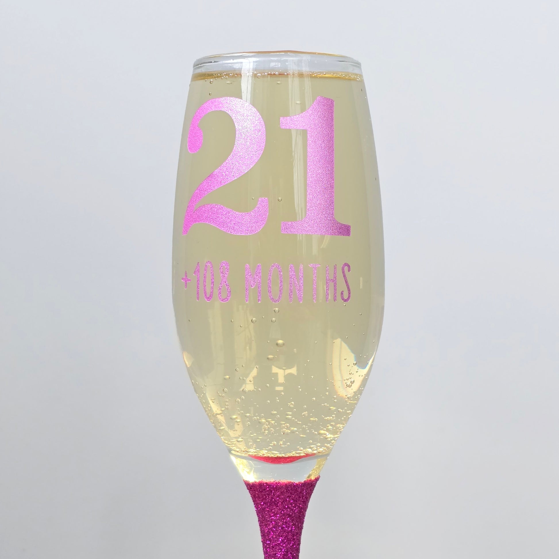 Prosecco glass or Champagne flute decorated with high shine glitter stem and personalised with 21 + the number of months to make up a 30th, 40th, 50th, 60th or 70th Birthday.