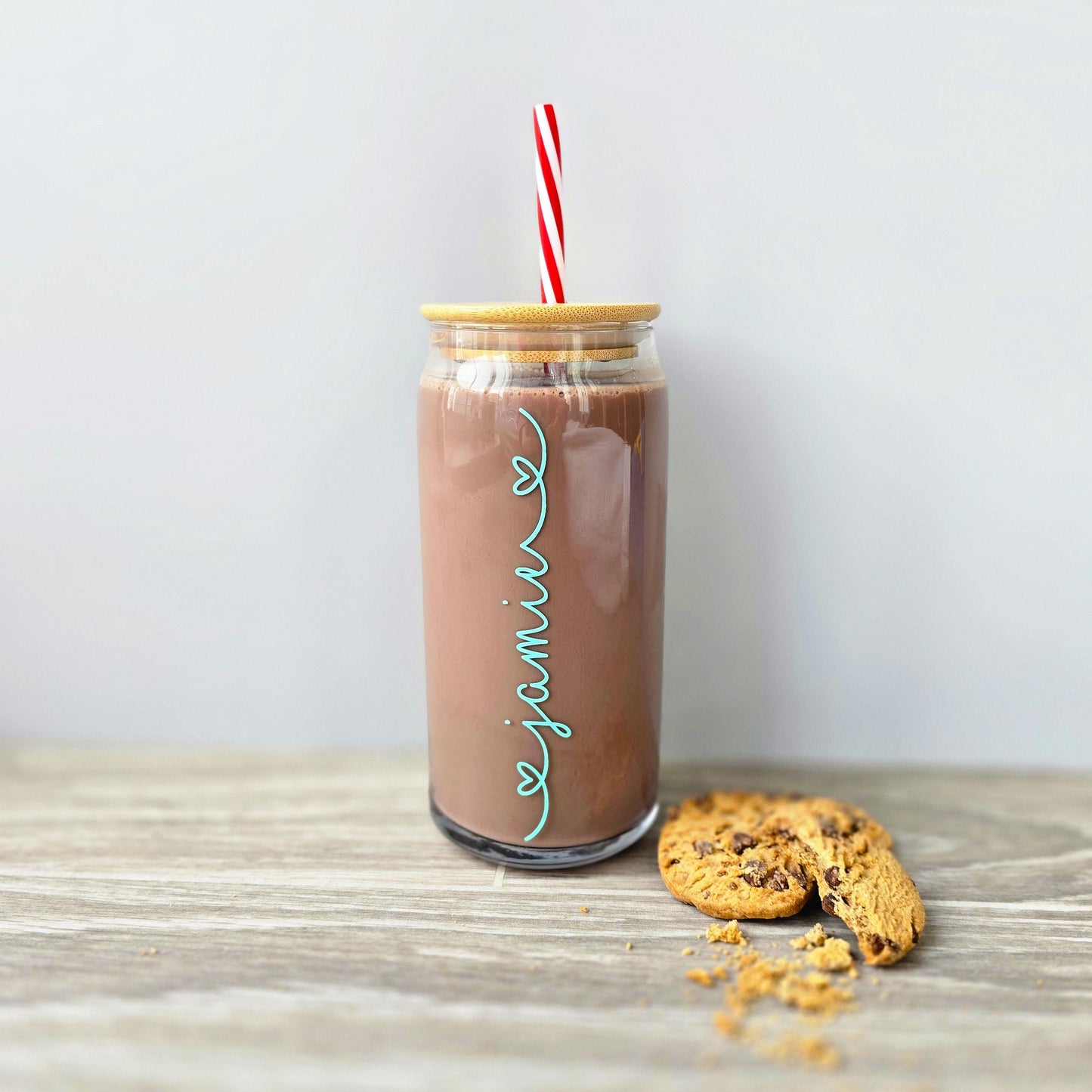 Personalised glass can drink tumbler with a bamboo suction lid and red and white reusable straw. Name printed in decorative font, in a range of colours, printed along the glass.
