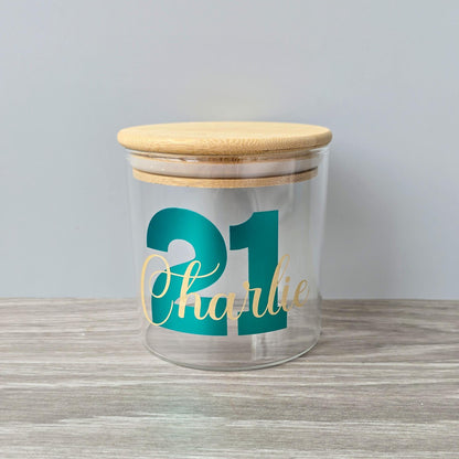 Personalised glass jar with wooden suction lid with a large age and name in metallic green and gold vinyl