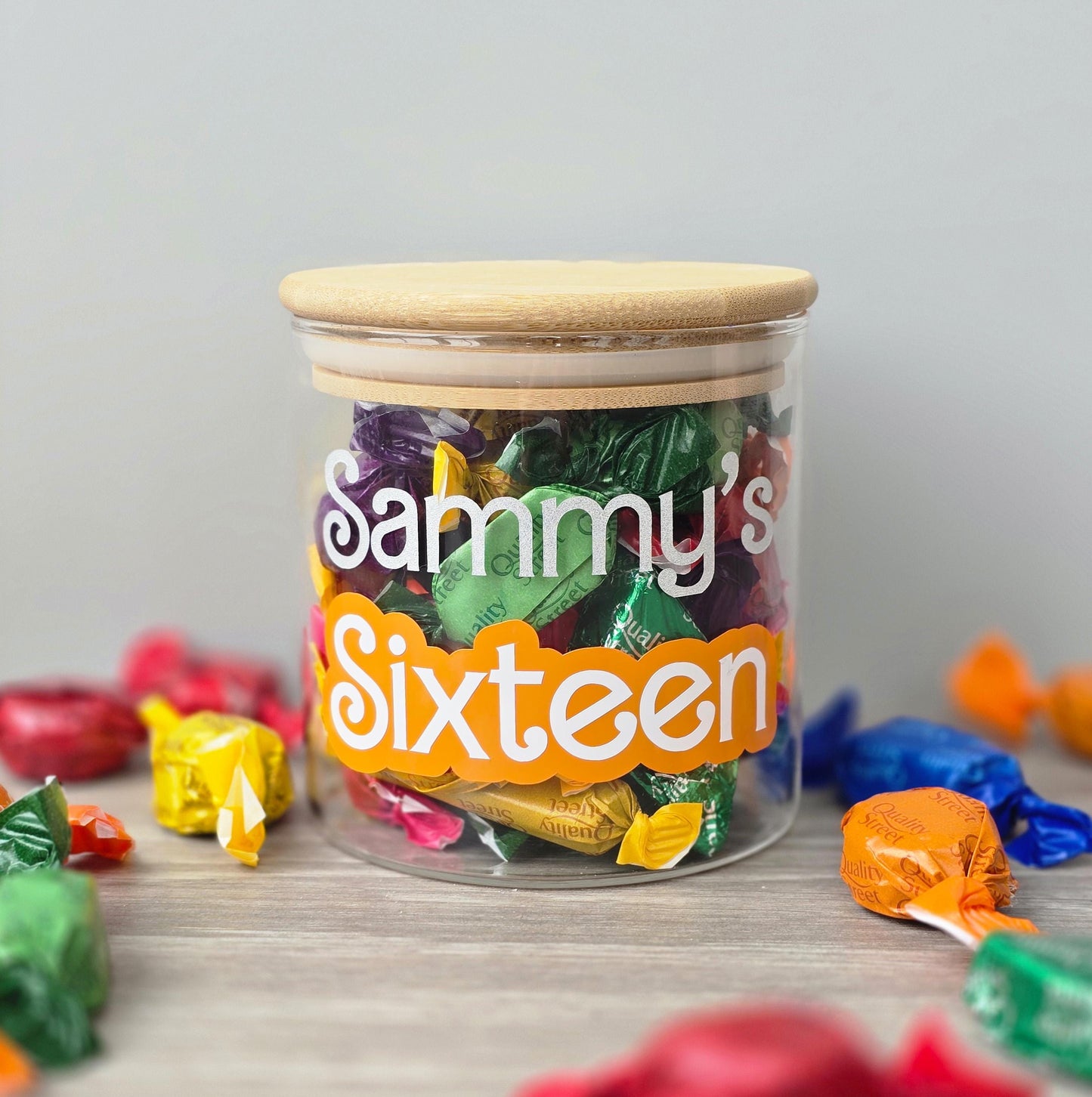 Jar of colorful candies with a personalized label on a light surface.