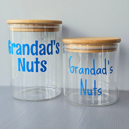 Two glass jars with wooden lids labeled 'Grandad's Nuts' on a grey background