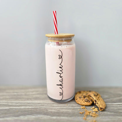 Personalised glass can drink tumbler with a bamboo suction lid and red and white reusable straw. Name printed in decorative font, in a range of colours, printed along the glass.