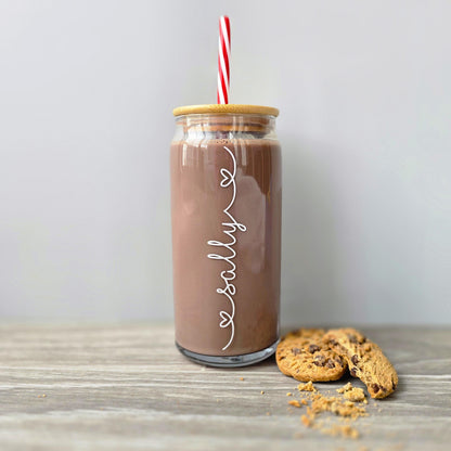 Personalised glass can drink tumbler with a bamboo suction lid and red and white reusable straw. Name printed in decorative font, in a range of colours, printed along the glass.