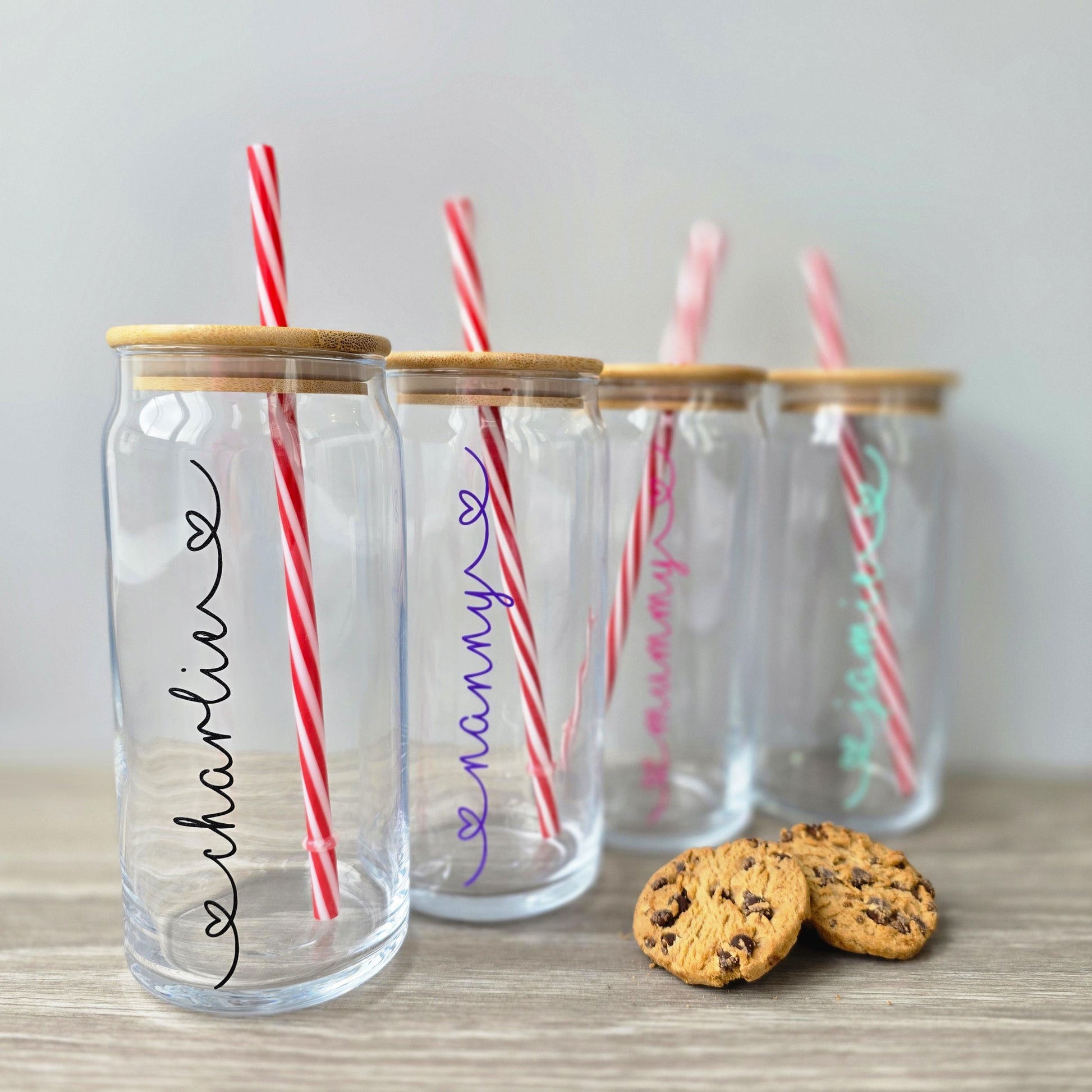 Personalised glass can drink tumbler with a bamboo suction lid and red and white reusable straw. Name printed in decorative font, in a range of colours, printed along the glass.