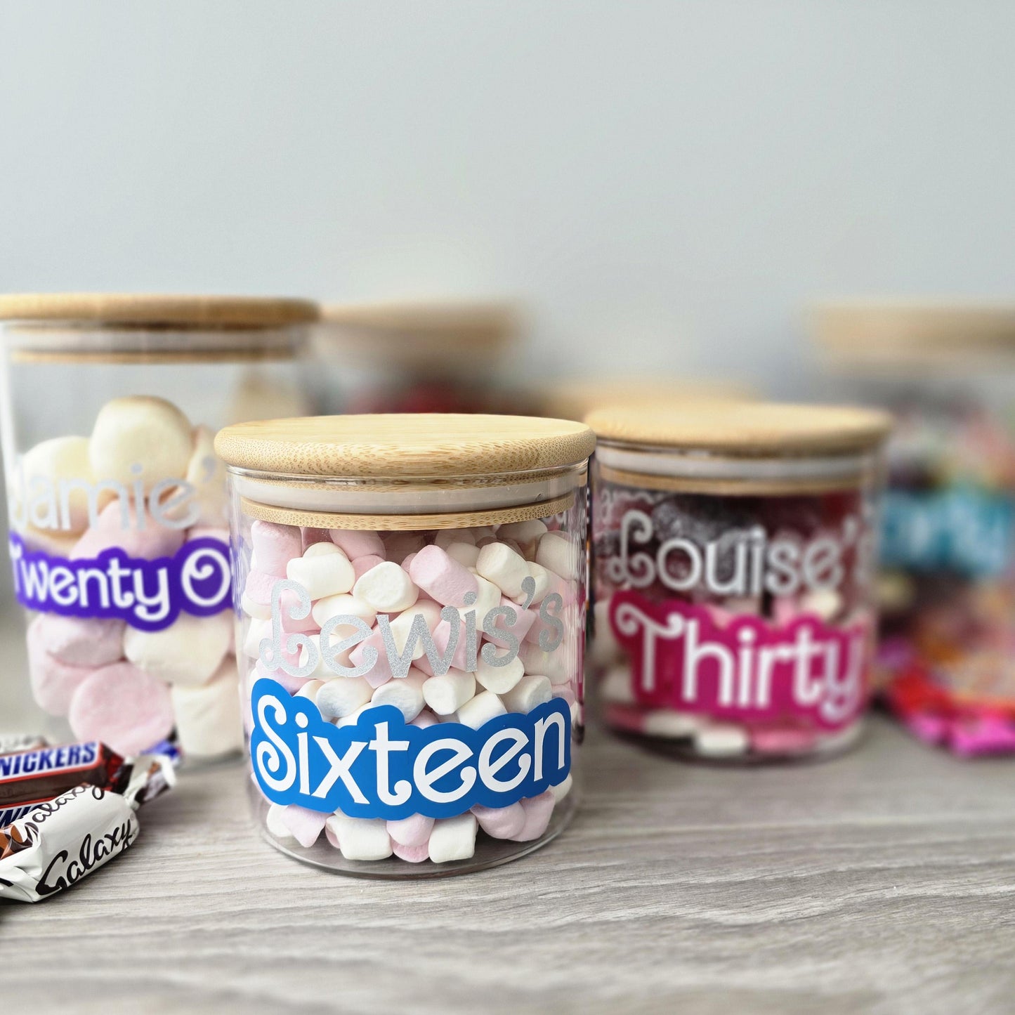 Decorative jars with personalized labels on a wooden surface