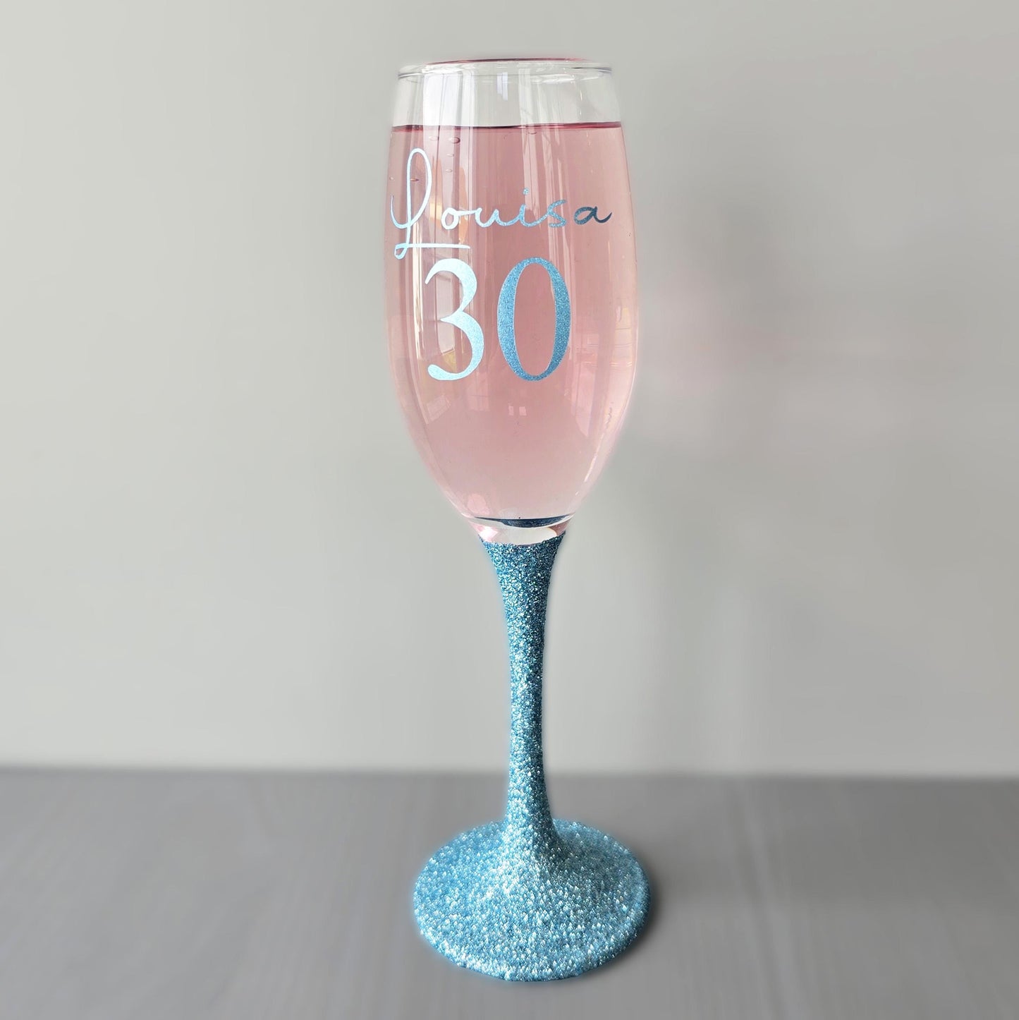 Personalised glitter stem prosecco glass or champagne flute in gold, pink, purple or Blue. Signature style custom name and an age underneath